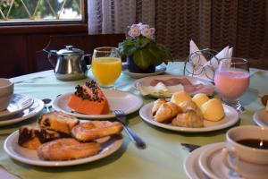 uma mesa com pratos de alimentos e bebidas ao pequeno-almoço em Pousada Sino dos Ventos- Hospedagem Afetiva em Campos do Jordão