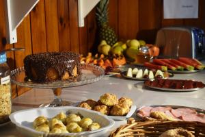 una mesa cubierta con un pastel de chocolate y otros alimentos en Pousada Sino dos Ventos- Hospedagem Afetiva, en Campos do Jordão