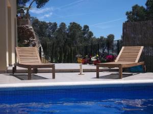 two wooden chairs sitting next to a swimming pool at Villa Hermosa in Begur