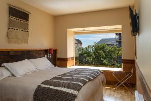 ein Schlafzimmer mit einem Bett und einem großen Fenster in der Unterkunft Casa Kalfu Hotel Boutique in Puerto Varas