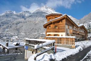 a large wooden building with snow on the ground at Casa Vacanza La Rocca in Chiesa in Valmalenco