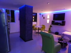ein Wohnzimmer mit einem Tisch, Stühlen und lila Leuchten in der Unterkunft Apartment Lux Bocagrande in Cartagena de Indias