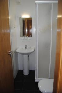 ein Badezimmer mit einem Waschbecken, einem Spiegel und einem WC in der Unterkunft Hotel Covilhã Jardim in Covilhã