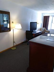Habitación de hotel con escritorio, ordenador y lámpara. en Hotel Blue Top Inn, en Stevens Point