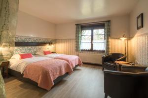 a bedroom with two beds and a chair and a window at Hotel Troopeird in Kortrijk