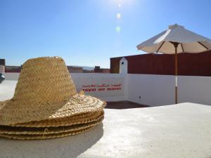 een strohoed op een tafel met een paraplu bij Tweets Hotel in Essaouira
