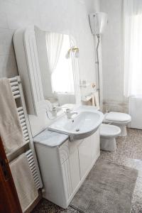 a white bathroom with a sink and a toilet at CasaVincy in Serradifalco