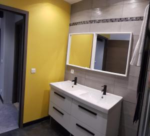een badkamer met een witte wastafel en een spiegel bij le Gîte Ginkg'home in Saint-Max