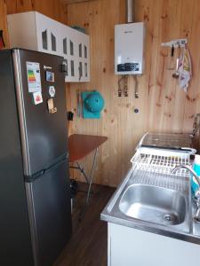 a kitchen with a refrigerator and a sink at Cabaña Sonido de Mar in Pichilemu +6 photos