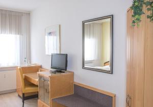 
a desk with a television and a chair in front of a window at Pension Tokus in Nuremberg

