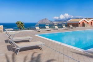 a swimming pool with lounge chairs and the ocean at Hotel Parco Degli Aromi Resort & SPA in Valderice