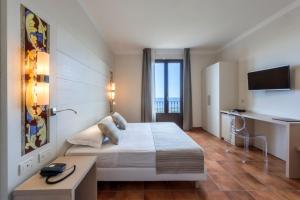 um quarto de hotel com uma cama e uma secretária em Hotel Parco Degli Aromi Resort & SPA em Valderice