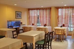 una sala da pranzo con tavoli, sedie e TV di Hotel Le Village a Gif-sur-Yvette