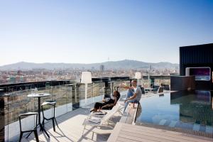 Ein Mann und eine Frau sitzen am Rand eines Daches in der Unterkunft Barceló Raval in Barcelona