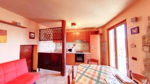 uma cozinha com um sofá vermelho e uma mesa num quarto em Casa Magotina em Tavernola Bergamasca