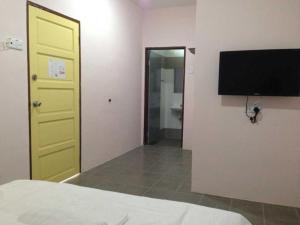 a bedroom with a yellow door and a television on the wall at First Guest House in Kuantan