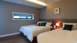 a hotel room with two beds and a window at Arts Spa&Poolvilla in Jeju