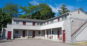 a large white house with red doors and windows at Sea Lion Motel in Gloucester
