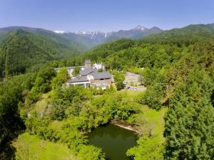 eine Luftansicht eines Hauses in den Bergen mit See in der Unterkunft Azumino Hotaka View Hotel in Azumino