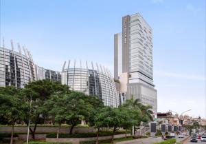 un grupo de edificios altos en una ciudad con árboles en Mercure Jakarta Pantai Indah Kapuk, en Yakarta