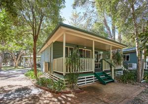 een klein groen huis met een veranda en een veranda bij Budgewoi Holiday Park in Budgewoi