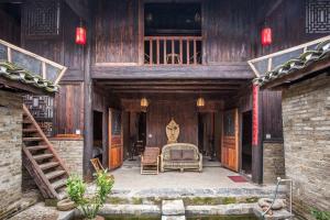 un edificio de madera con una cama y sillas. en Laojia, a Qing dynasty house, en Xingping