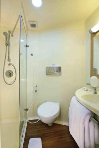 
a bathroom with a shower, toilet, and sink at Cordela Hotel Cirebon in Cirebon
