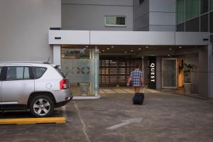 a man pulling a suitcase in front of a building at Quest Suva in Suva