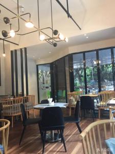 a dining room with tables and chairs and windows at Paco Hotel Gangding Metro Guangzhou-Free Shuttle Bus fir Canton Fair in Guangzhou