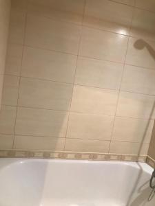 a bath tub in a bathroom with a tile floor at Studio At Dnipro Naberezhnaya in Dnipro