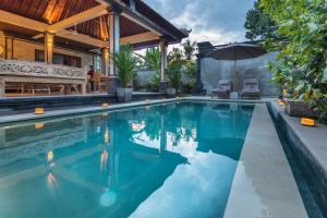 een overloopzwembad in een huis met een parasol bij Secret Bunutan Ubud Villa in Ubud