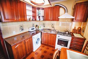 een keuken met houten kasten, een wastafel en een fornuis bij 2-bedroom on Mykolaychuka street in Vinnytsya