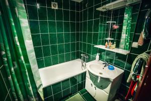 een groene betegelde badkamer met een bad en een wastafel bij 2-bedroom on Mykolaychuka street in Vinnytsya +11 foto's
