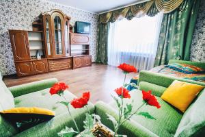 ヴィーンヌィツャにある2-bedroom on Mykolaychuka streetの緑のソファと赤い花が飾られたリビングルーム