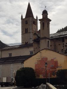 Un vieux bâtiment avec une tour et une horloge. dans l'établissement Hôtel Fleur des Alpes, à La Brigue