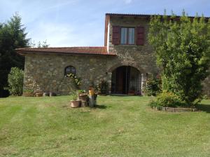 a stone house with a grass yard in front of it at Agriturismo La Casa Bianca in Poppi