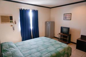 1 dormitorio con 1 cama y TV en Crowne Garden Hotel, en Cebú