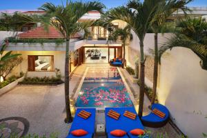 an indoor pool in the middle of a house with palm trees at Villa Mawar Legian in Legian