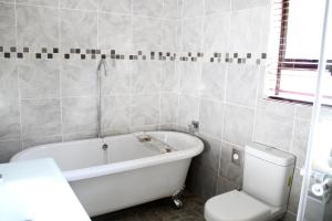 a bathroom with a white tub and a toilet at Tinyiko Kruger Lodge in Marloth Park +26 photos