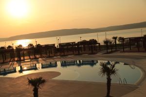 a swimming pool with the sun setting over the water at Kolin Hotel Spa & Convention Center in Çanakkale