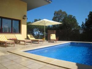 a swimming pool with two chairs and an umbrella at Villa Hermosa in Begur