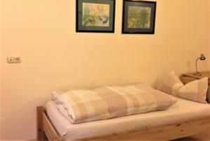 Bett in einem Zimmer mit zwei Bildern an der Wand in der Unterkunft Ferienwohnung Drößler in Mühlhausen