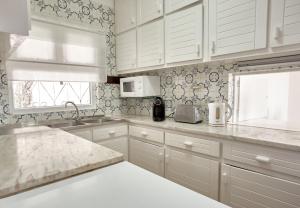 a white kitchen with white cabinets and a sink at E&M Beach House Aldeamento do Levante II in Lagoa