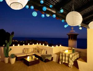 d'une terrasse avec un canapé, des tables et des lumières. dans l'établissement E&M Beach House Aldeamento do Levante II, à Lagoa