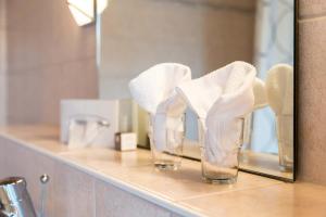 two glasses with white towels on a shelf in a bathroom at Landhotel Huber am See in Münsing am Starnberger See