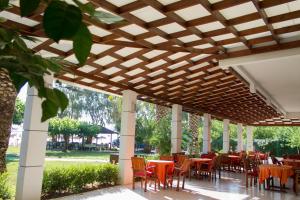 une terrasse avec des tables et des chaises sous une pergola en bois dans l'établissement Hotel Hellas, à Ancient Epidavros