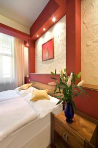- une chambre avec un lit et un vase de fleurs dans l'établissement Spa & Wellness Hotel St. Moritz, à Mariánské Lázně