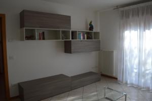 uma sala de estar com prateleiras de madeira na parede em Appartamenti "Venice" em Noventa di Piave