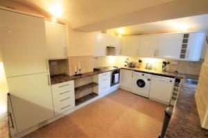 a kitchen with white cabinets and a washer and dryer at Meridian Way - 3 Bed Apartment - Sleeps 7 in Bristol