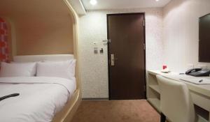 a bedroom with a bed and a desk and a door at Hotel Leisure 台中輕行旅 in Taichung